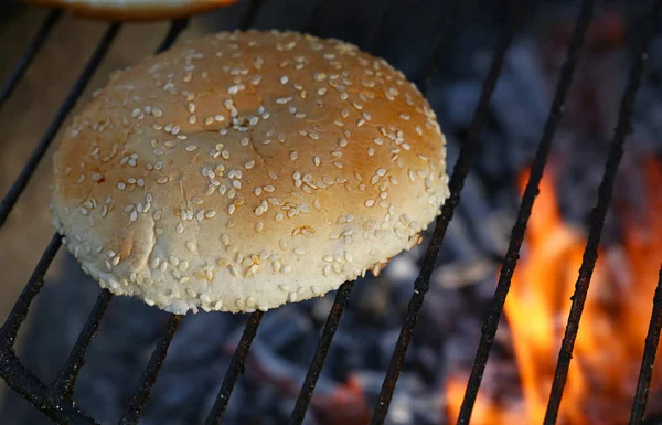 Close up pão de gergelim para hambúrguer na churrasqueira fogo — Fotografia de Stock