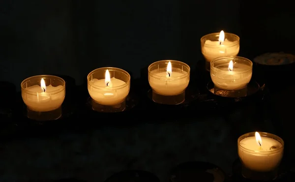 Bougies blanches brûlant dans l'église sombre gros plan — Photo