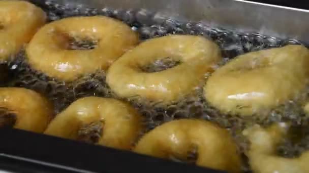 Close-up van diepe frituren ring donuts in olie — Stockvideo