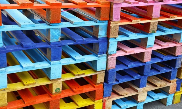 Pilha de muitas paletes de madeira pintadas multicoloridas — Fotografia de Stock