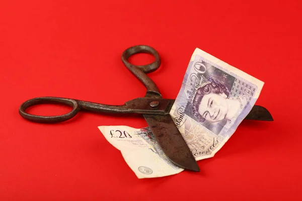 Scissors cut British Pound over red background