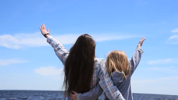 Woman, young, girl, small, mother, daughter, rear, view, close-up, day, sky, blue, wind, hair, long, dark, blond, hands, raise, low, angle, view, shake, play, move, hug, embrace, family, together, toge — Vídeo de Stock