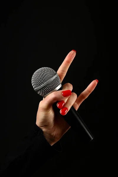 Woman hand with microphone and devil horns isolated on black — Stock Photo, Image