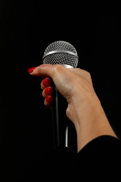 Mano donna con microfono isolato su nero — Foto Stock