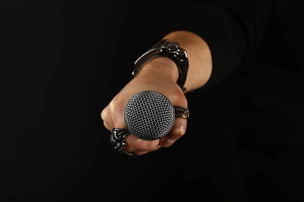 Man handen med mikrofon isolerade på svart — Stockfoto