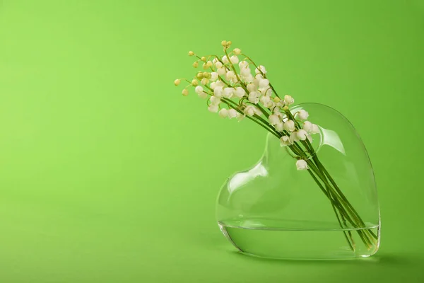 Lilly of the valley in heart shaped vase on green — Stock Photo, Image