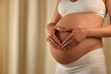 Holding ve maruz karnı Bebek Doğum tahmin kalp şeklinde ellerimle dokunmadan hamile beyaz bir kadın profili görünümünü kapat