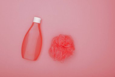 Bir şişe duş jeli ve kadınsı yumuşak banyo derisini kapatın. Pembe arka planda fırçalayın. Üst manzara, tam üstte.