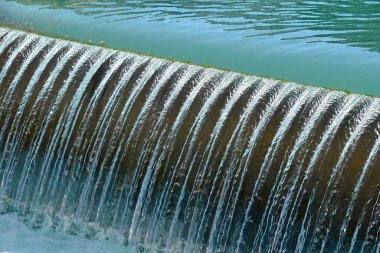 Turkuaz mavi nehir suyu, iskeleden dökülen köstebek yarığı ve köpürmesi, yüksek açılı çapraz görüş.