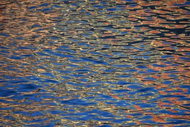 Canlı mavi ve turuncu su dalgaları ve dalgaların soyut arkaplanı, deniz yüzeyindeki yansıma, yüksek açı görüntüsü