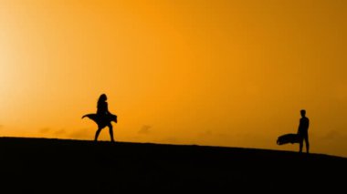 Sunset bulvarında bir kumsalda dans siluet