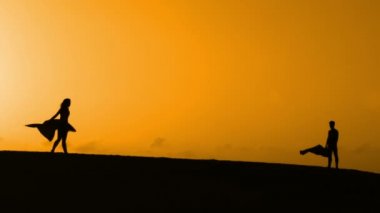 Sunset bulvarında bir kumsalda dans siluet