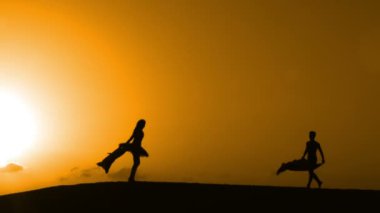 Sunset bulvarında bir kumsalda dans siluet