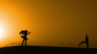 Sunset bulvarında bir kumsalda dans siluet