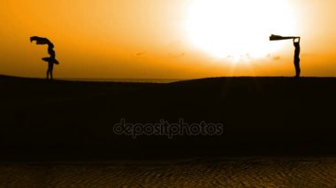 Sunset bulvarında bir kumsalda dans siluet