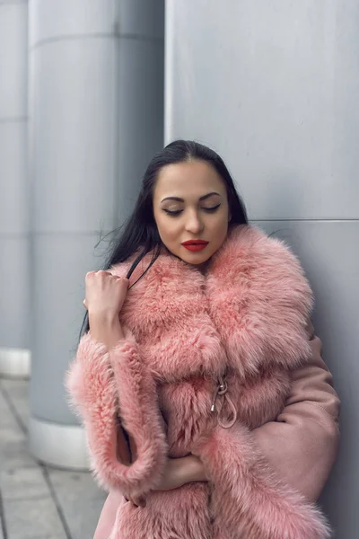 Morena en la ciudad en un abrigo rosa —  Fotos de Stock