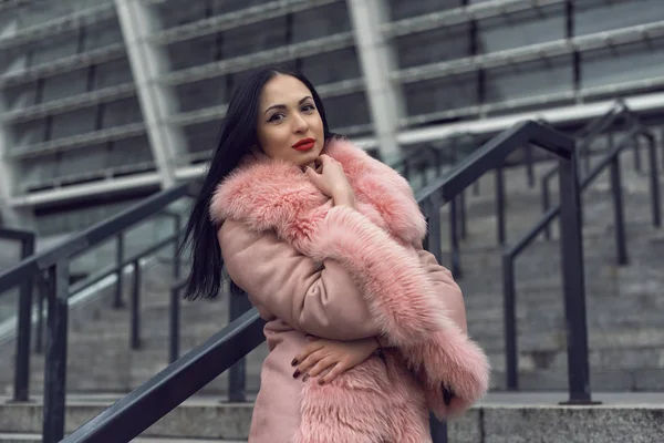 Morena en la ciudad en un abrigo rosa —  Fotos de Stock