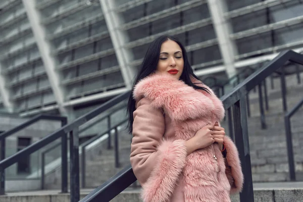 Bruneta ve městě v růžovém kabátě — Stock fotografie