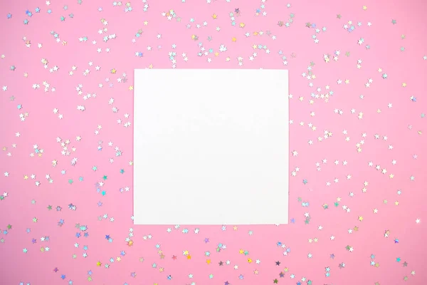 Boş beyaz kare kağıt kart ve holografik yıldız konfetileri pembe model üzerinde yatıyordu