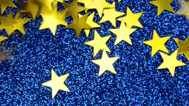 Étoiles tombées espace ciel sombre. Confettis jaunes dorés sur fond macro à paillettes bleu classique — Video