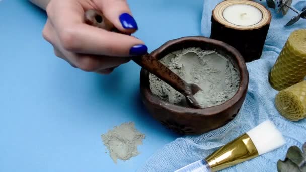 Hand with blue nails manicure stir the cosmetic clay mask ingredients. Hand made beauty skin care face mask preparing — Stock Video