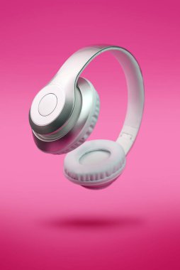 Neon pembe arka planda beyaz, lüks, taşınabilir kulaklıklar. Havada uçan son moda, yakın çekim konsepti.