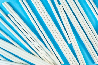 Bir sürü beyaz kağıt tüp mavi arka planda rastgele dağılmış. Manzara kokteyl tüpü dokusu. Makul tüketim. Hasır klipsli deseni kapat. Çevre dostu organik çöpler. Sıfır atık