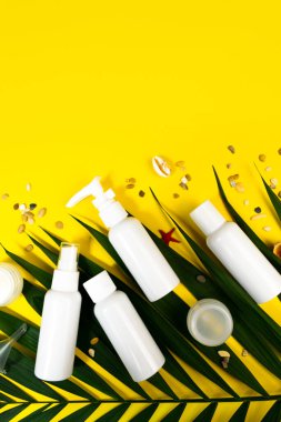 Yaz ağaçlarının boyutu kozmetik ürünleri sarı arka planda yatıyordu. Örnek uçak seti. Seyahat konsepti. Palmiye yaprağı, deniz kabukları, deniz bayrağı