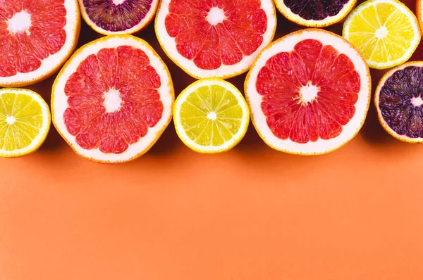 Many variety citrus fruits in a row flat lay in sunlight on orange background. Summer grapefruit orange lemon juice or healthy food concept. Banner design template, wallpaper, border, space for text