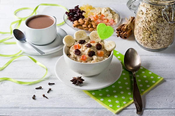 Yulaf lapası Kuruyemiş, kızılcık, muz ve baharatlar ile. Fincan kakao ve arka plan üzerinde yulaf ezmesi kavanozu. Beyaz arka plan üzerinde düzenlenmiş.