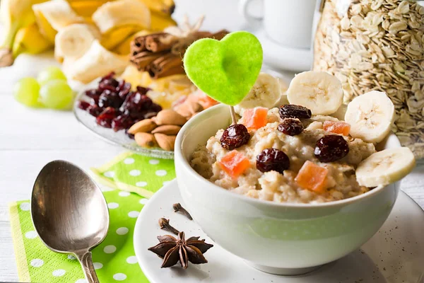 Oatmeal porridge with dried fruits, cranberries, bananas and spices. Jar of oatmeal on background. Arranged on white background. — Stock Photo, Image