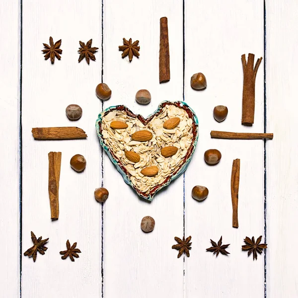 Background made of various types of spices. Centrally in the frame clay bowl in the shape of a heart. — Stock Photo, Image
