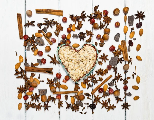 Background made of various types of spices. Centrally in the frame clay bowl in the shape of a heart. — Stock Photo, Image