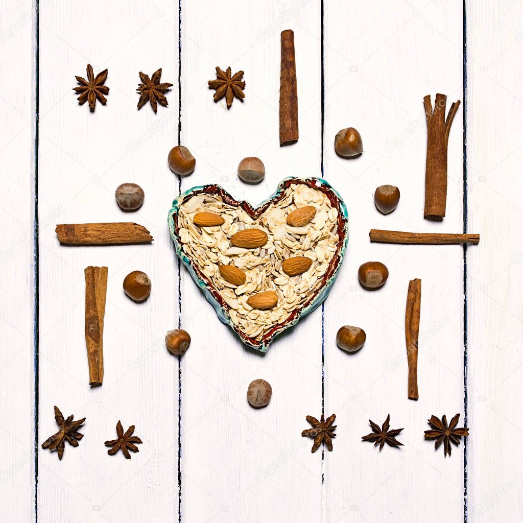 Background made of various types of spices. Centrally in the frame clay bowl in the shape of a heart.