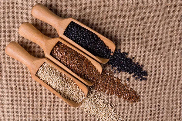 Soczewica, nasiona lnu i quinoa w drewnianą łyżką. — Zdjęcie stockowe