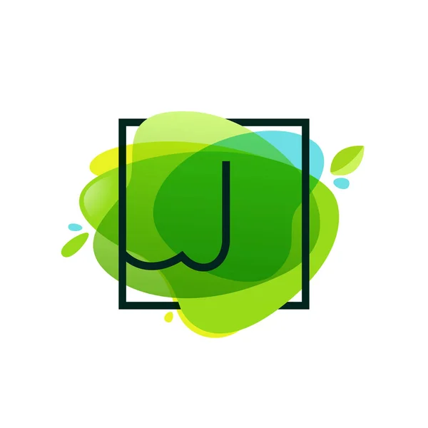 J brev logotyp i fyrkantig ram på gröna akvarell splash backgro — Stock vektor