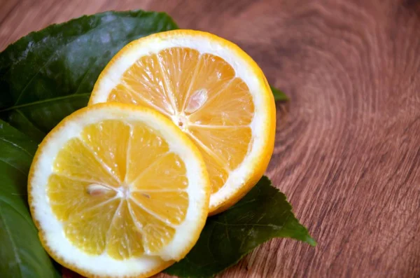    Limon yaprakları ile dilimlenmiş. Ahşap arka plan üzerinde. Üstten Görünüm