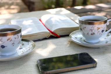 ahşap masa açık kitap, birkaç bardak kahve