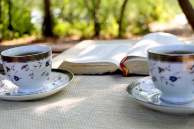 ahşap masa açık kitap, birkaç bardak kahve
