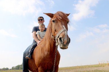 Küçük yakışıklı sevimli oğlu ve sahada kırmızı atı ile güneş gözlüğü moda adam.