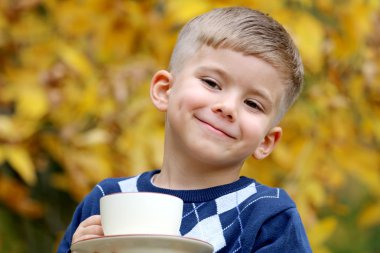 küçük çocuk gülümseyen güzel sarışın bir fincan doğada tutar 