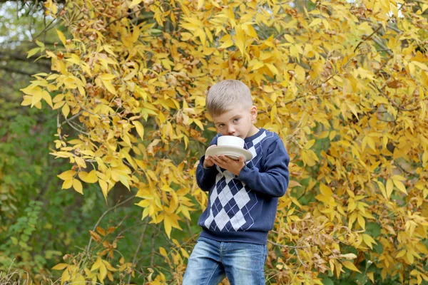 Krásná blondýna usmívá malý chlapec drží pohár v přírodě — Stock fotografie