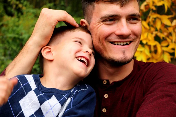 Padre sostiene a su hijo en sus brazos, padre e hijo jugando juntos al aire libre en el bosque — Foto de Stock