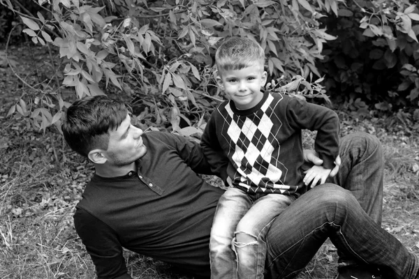 Padre sostiene a su hijo en sus brazos, padre e hijo jugando juntos al aire libre en el bosque — Foto de Stock