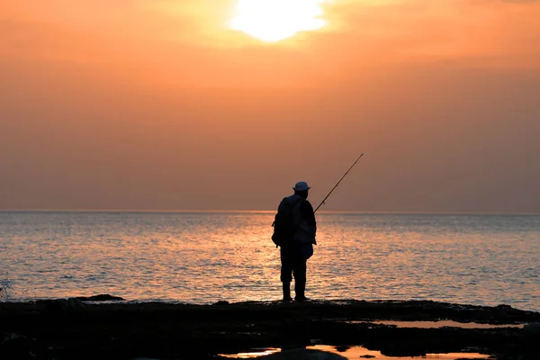 Pêcheur quand le soleil attraper des poissons de mer sur la filature sur les pierres — Photo