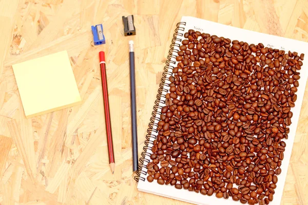 Kaffeebohnen Auf Einem Notizbuch Mit Einer Reihe Von Büros — Stockfoto