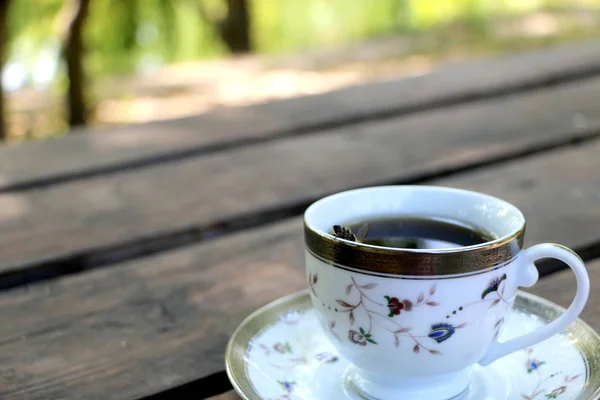 cup full of coffee on the table in nature, the bee in a cup