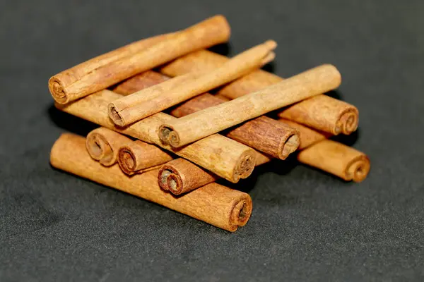Palillos de canela expuestos en una fila, corteza de árbol —  Fotos de Stock