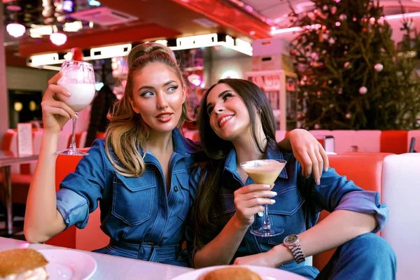 Mujeres Jóvenes Apasionadas Bebiendo Sabrosos Cócteles Sentados Mesa Cafetería Riendo —  Fotos de Stock