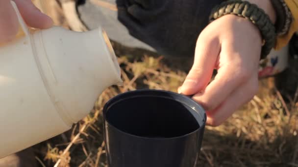 Mann gießt Tee aus Thermoskanne auf die Natur — Stockvideo